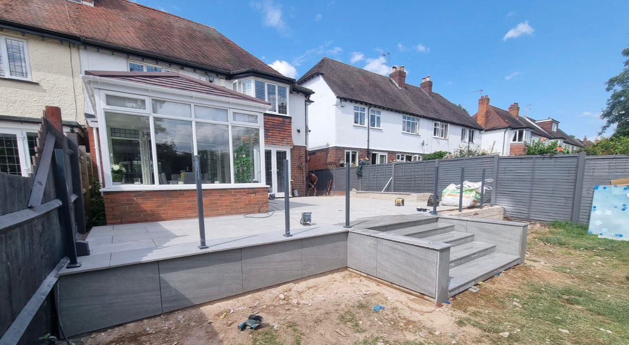 Dark composite decking installed beside a brick house